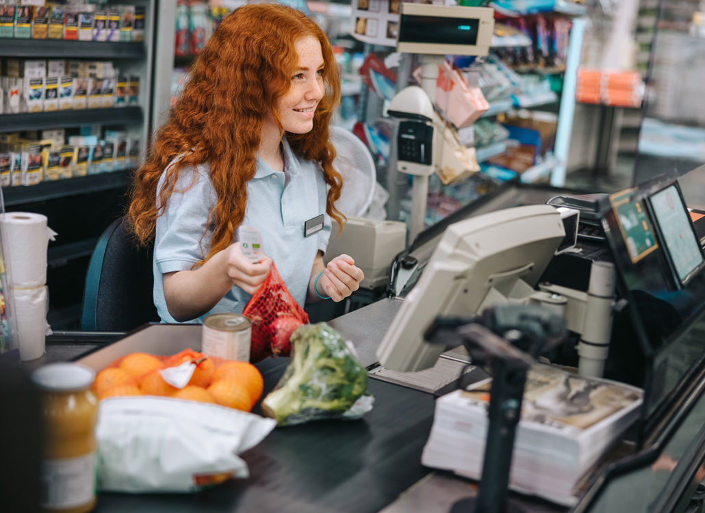 En kassemedarbejder i et supermarked scanner varer og hjælper en kunde for en hurtig og problemfri shoppingoplevelse.