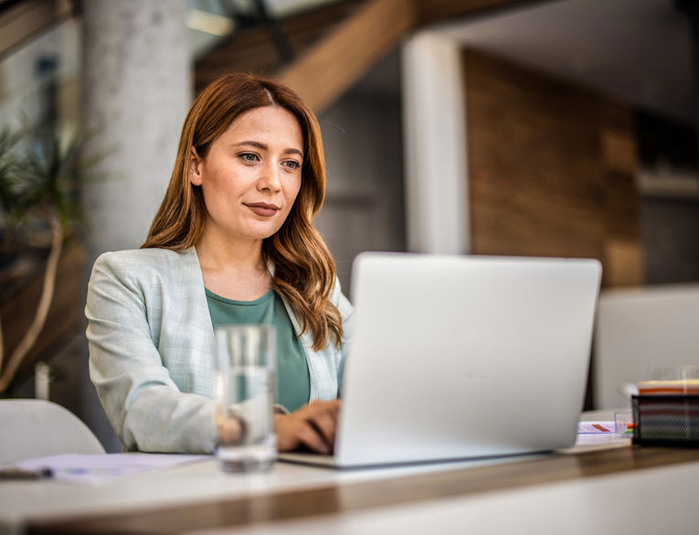 Manager using a digital workforce management system for shift scheduling and time tracking while working on a laptop.